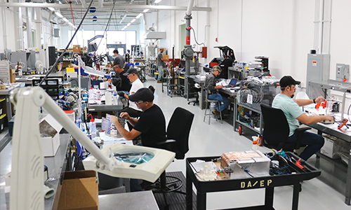Photo of people busy at their workbenches on the ACT production floor